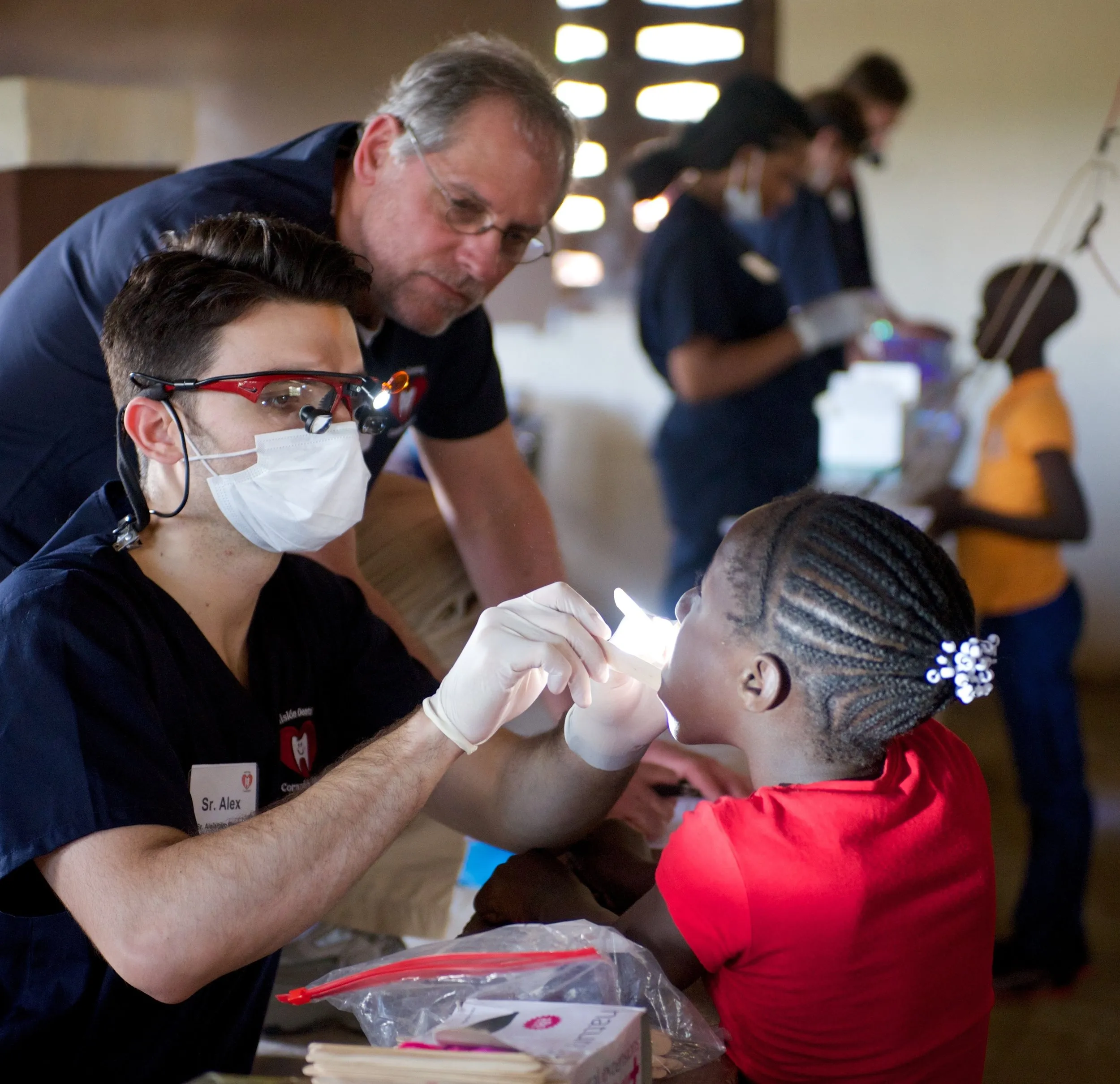 A volunteer dentist examines a young child's teeth