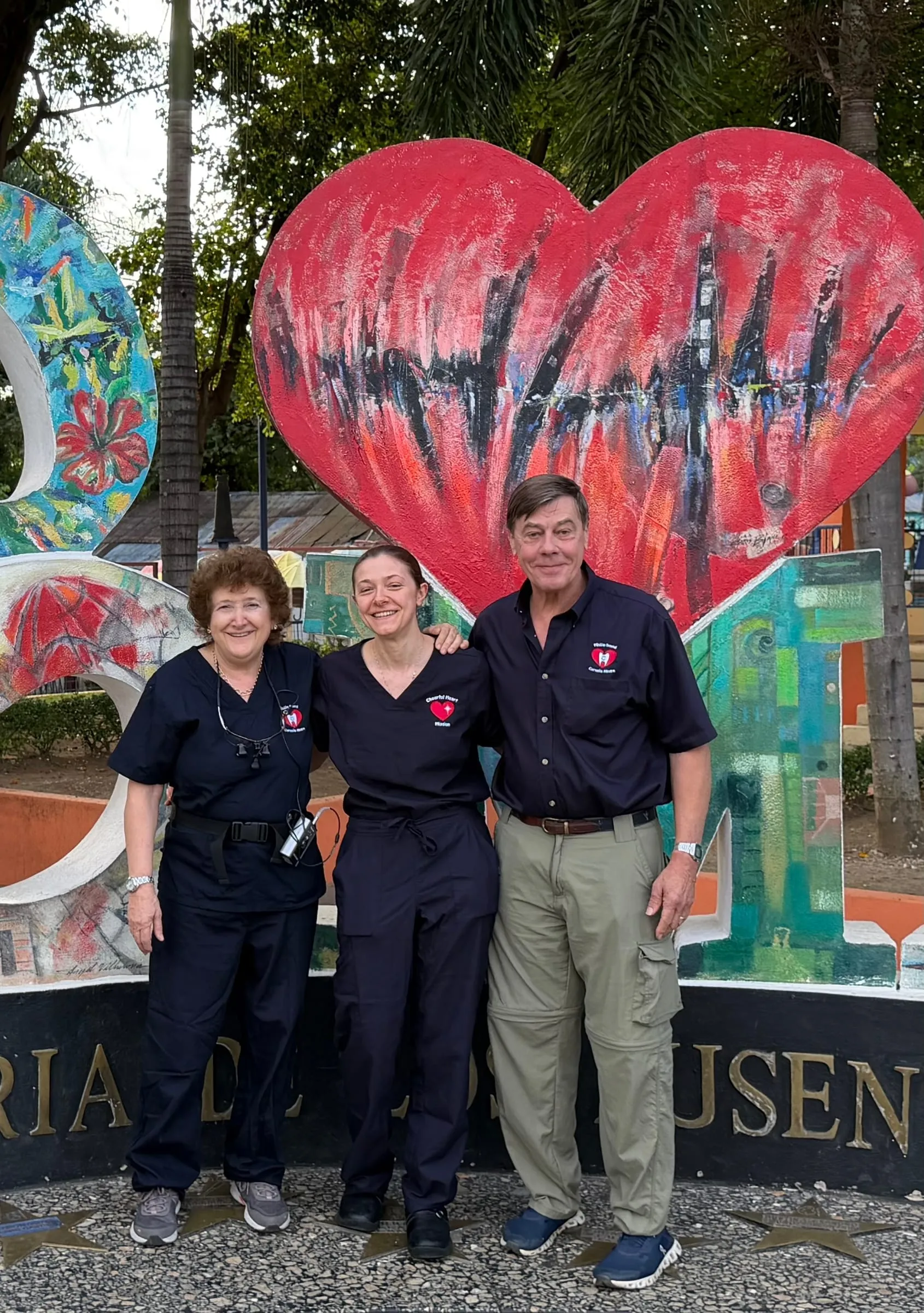 Three volunteers at a red heart mural
